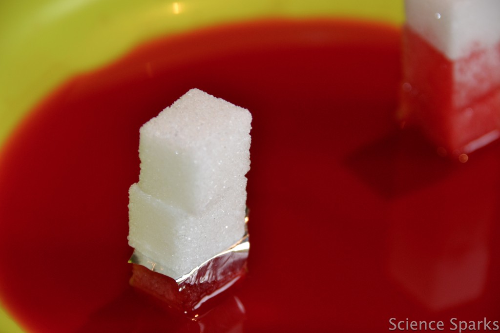 three sugar cubes stacked up on a plate with red water