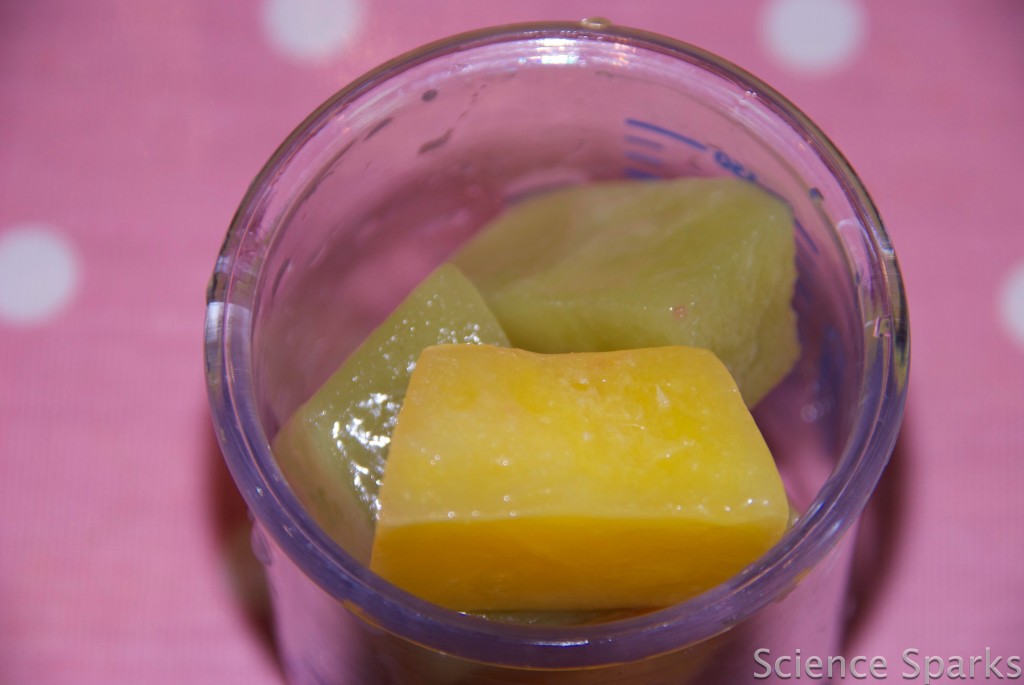 Cube of yellow and green frozen smoothie in a glass
