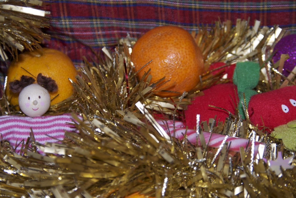 orange, tinsel and Christmas decorations in a basket for a festive sensory box