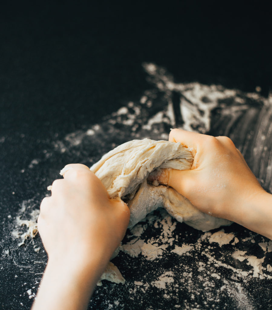 Pizza dough being kneaded by a child's hands