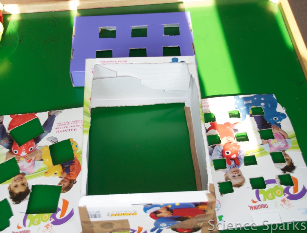 cardboard box with square holes cut into it to be used as a DIY toy sorter.