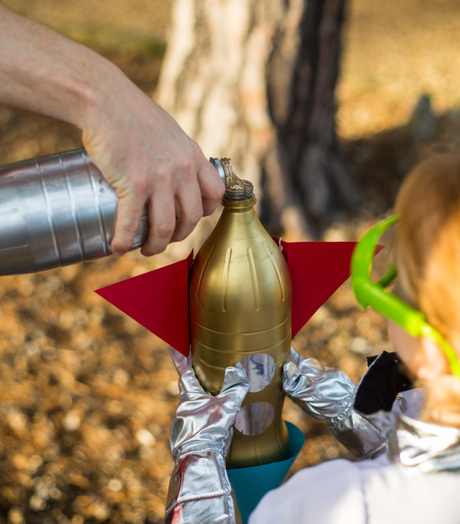How to make a Bottle Rocket - mans hand pouring water into a bottle rocket