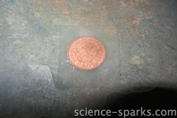 two pence coin covered in water and kitchen towel
