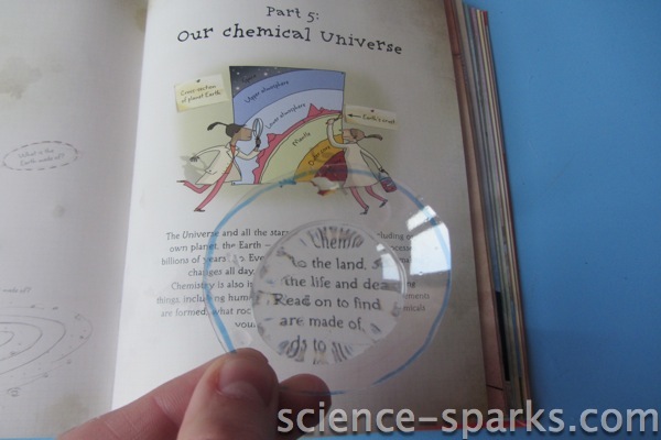a segment cut from a plastic bottle being used over a book as a magnifying glass