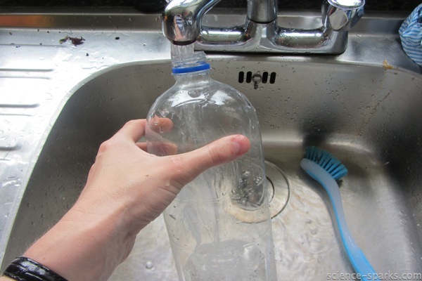 plastic bottle being held under a tap for a bubble science activity