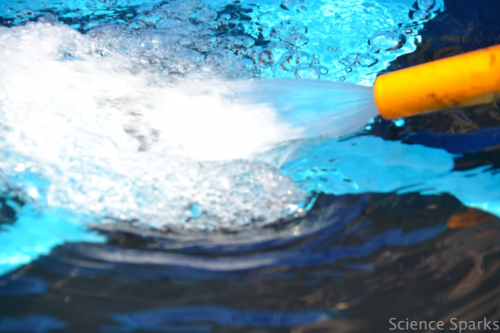 hosepipe spraying water into a paddling pool