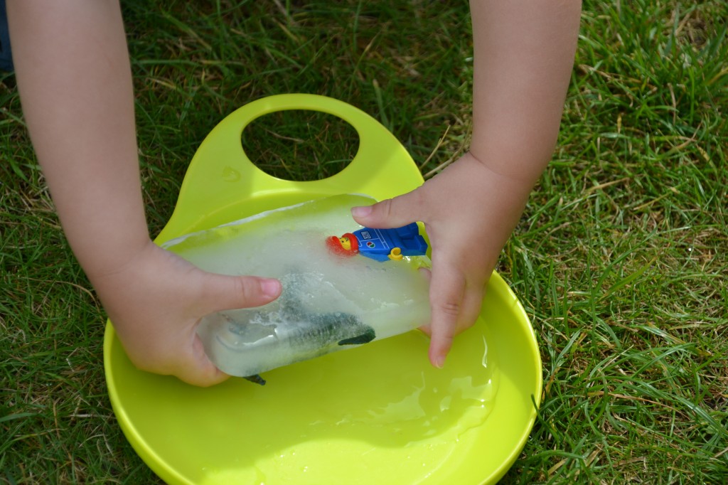 Child holding a giant ice cube with a LEGO man frozen inside