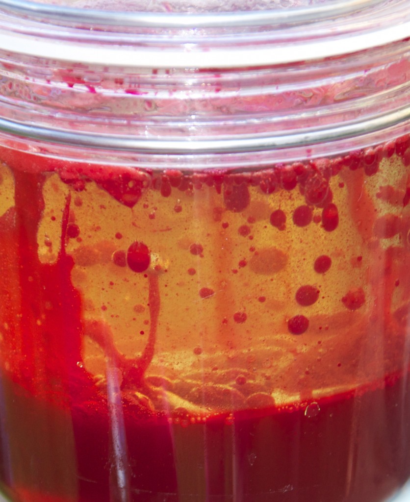 homemade lava lamp close up image showing red food colouring and water bubbles rising up through vegetable oil