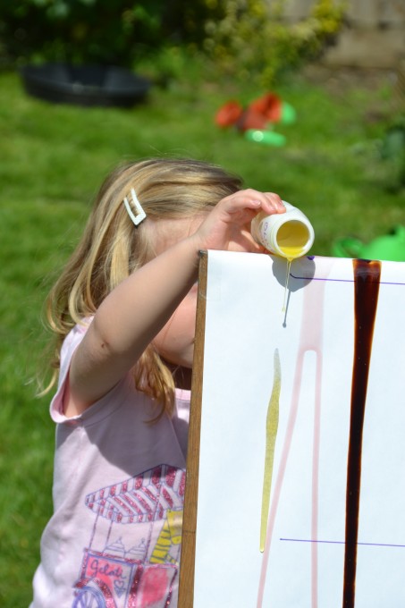 child pouring a container of oil down a ramp for a viscosity experiment