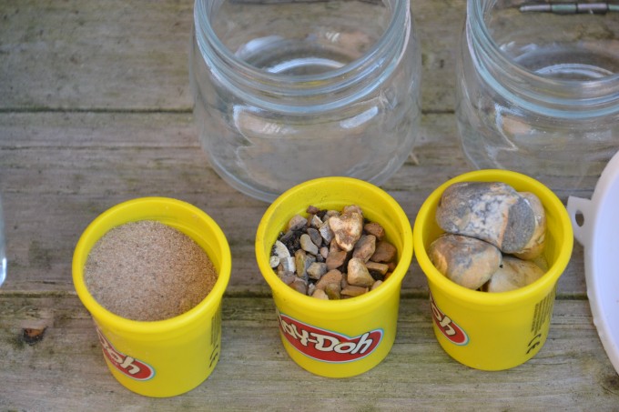 three containers containing sand, small stone and large stones for a filtering experiment