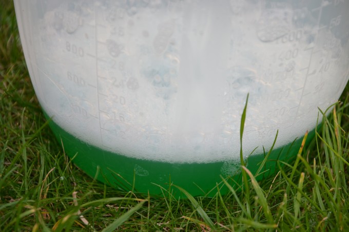 green bubble mixture in a container on the grass