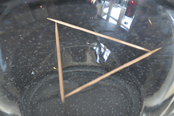 3 cocktail sticks lying on a bowl of water in a triangle shape