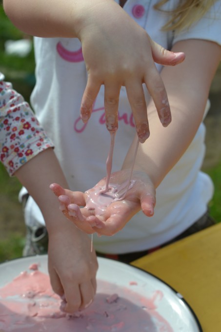 Two girls playing with pink coloured oobleck