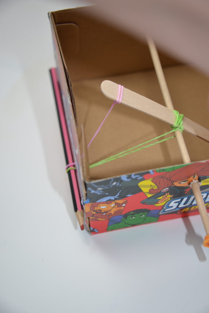 shoebox catapult showing an elastic band holding the catapult arm in place and secured with a pencil