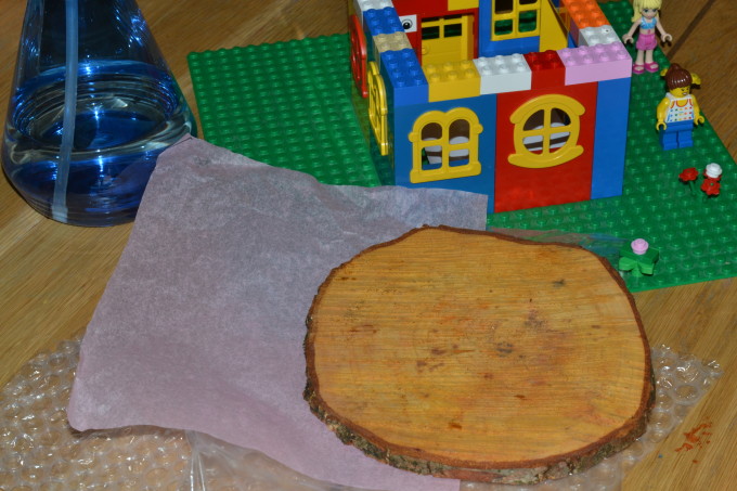 Small lego house, wood, paper and a water bottle for a testing a roof to see if it is waterproof science experiment