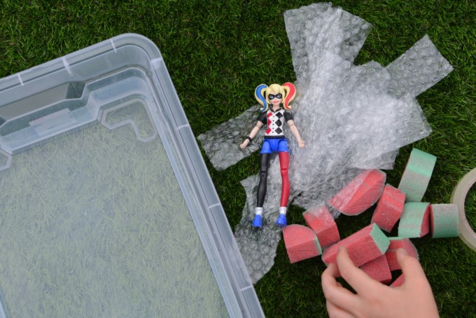 Image of a suoerhero toy figure surrounded by bubble wrap and pool noodle pieces