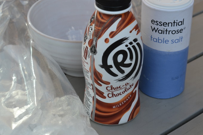 Image of chocolate milk, ice, salt and a bag - ingredients for making ice cream using ice and salt.