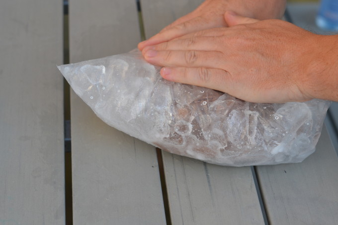 two child's hands on a bag of ice with chocolate milk inside a second bag for a science experiment making ice cream