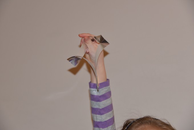 child's hand holding up a paper spinner for a science experiment