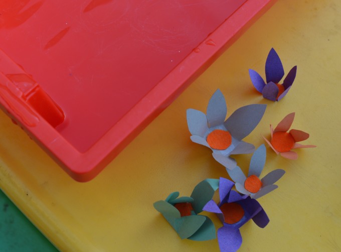 Image of a tray of water and flowers made from paper ready to put in the water
