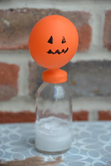 Blow up a balloon with alka seltzer. Image shows a small orange balloon partially inflated on top of a small glass jar.