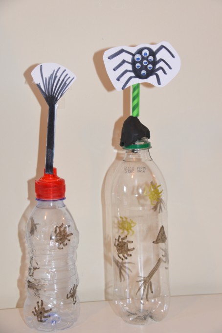 two plastic bottles with straw spiders on the top as part of a science experiment to learn about forces