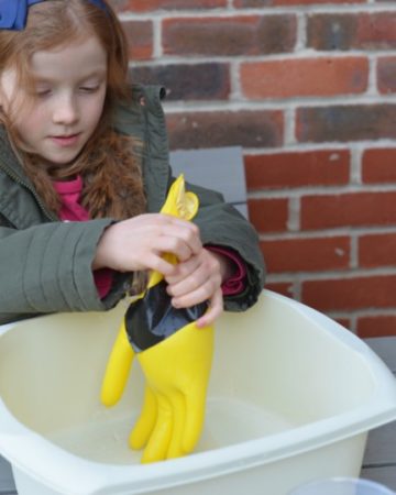Little girl testing a glove for holes as part of a space science activity