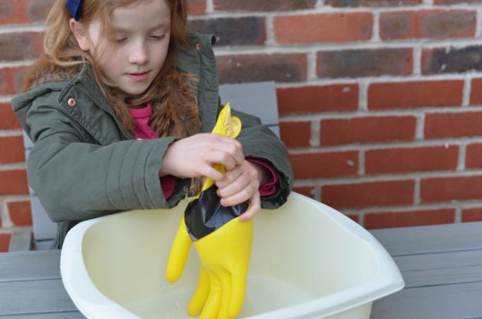 Little girl testing a glove for holes as part of a space science activity