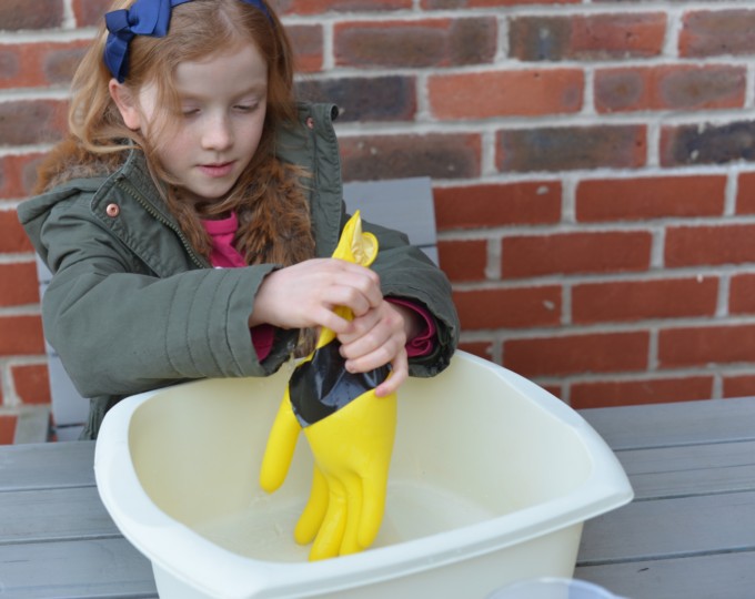 Little girl testing a glove for holes as part of a space science activity