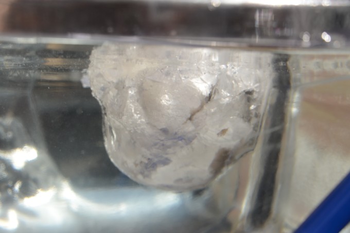  lump of ice floating in a water table. the image shows that most of the ice is under the water.