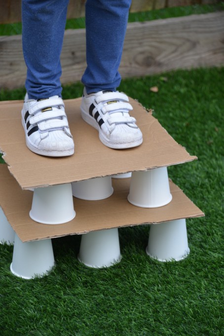 Child stood on paper cups with cardboard on the top