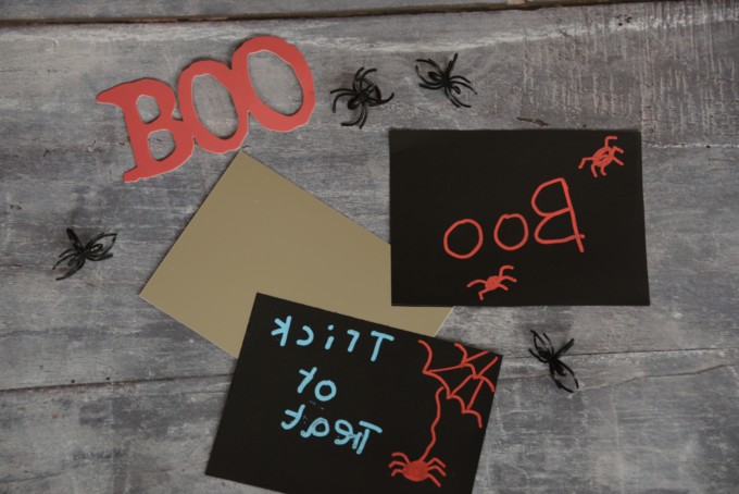 plastic spiders and backwards writing on black card for a Halloween science activity