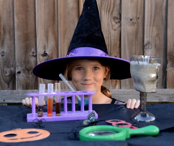 Witches laboratory set up in a garden with test tubes, magnifying glass and gloop. A great Halloween science activity for kids