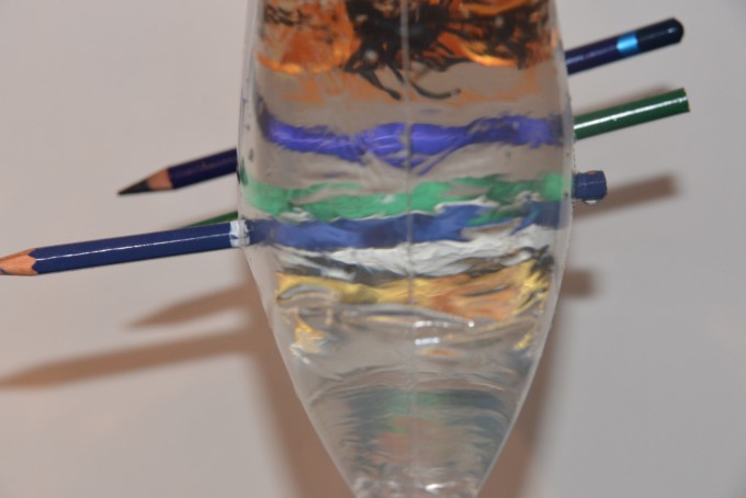 plastic bag filled with water with 6 pencils pushed all the way through to demonstrate a leakproof bag