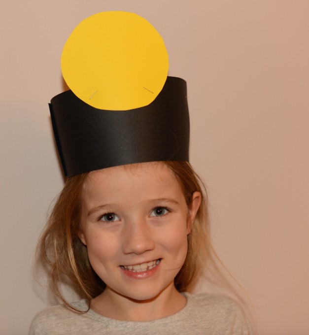 Child with a cardboard hat with a picture of the sun for an activity learning about Copernicus and Heliocentrism.