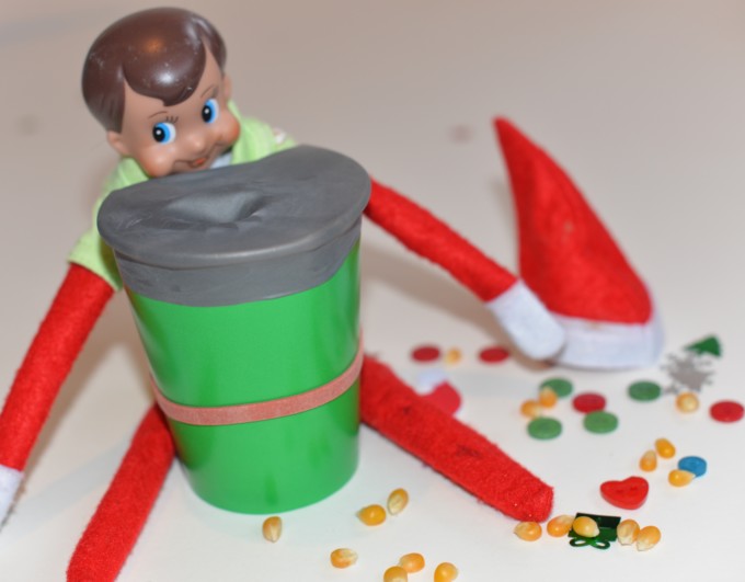 Elf sat behind a cup filled with noisy items