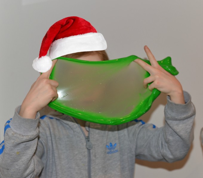 Child holding green slime stretched between two hands for a Grinch activity