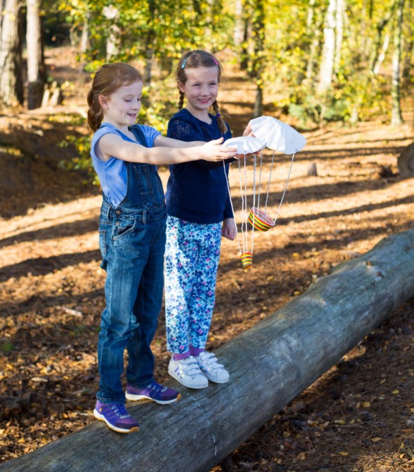 Children dropping a coffee filter parachute from a space science book for kids