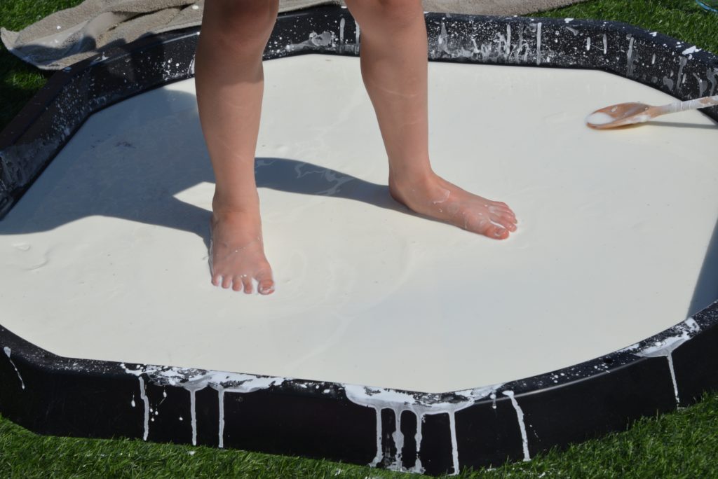 child standing in a giant black tray of oobleck