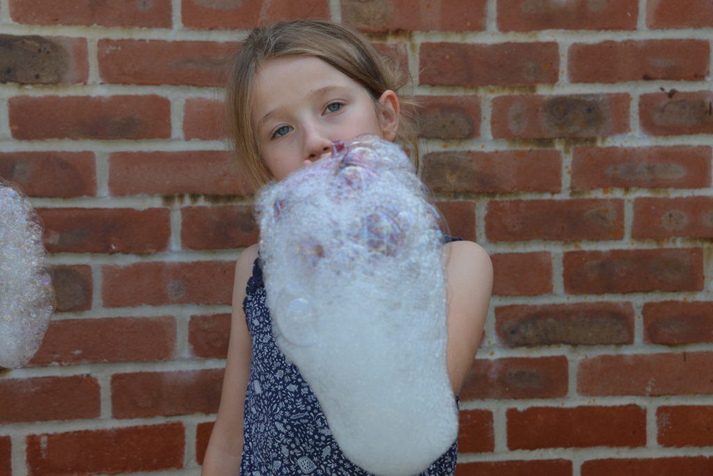 child blowing down a bubble snake as part of a science experiment