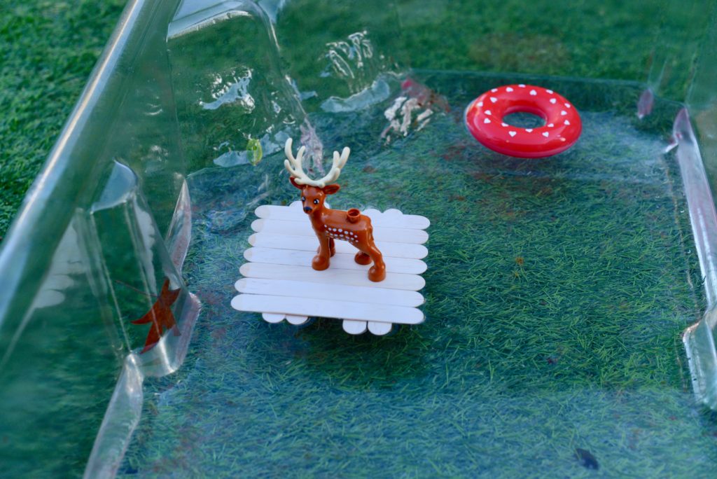 reindeer sat on a homemade lolly stick raft in a container of water for a Christmas STEM challenge