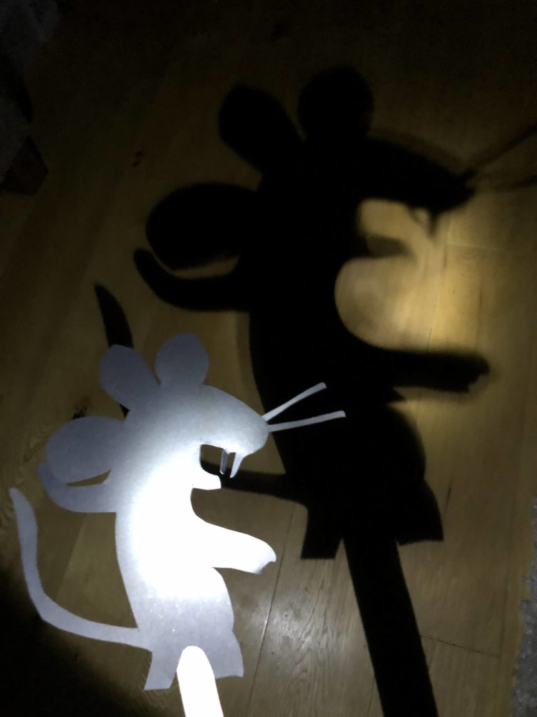 Gruffalo Mouse Shadow Puppet, a torch is behind the shadow puppet and there is a large shadow on the wall