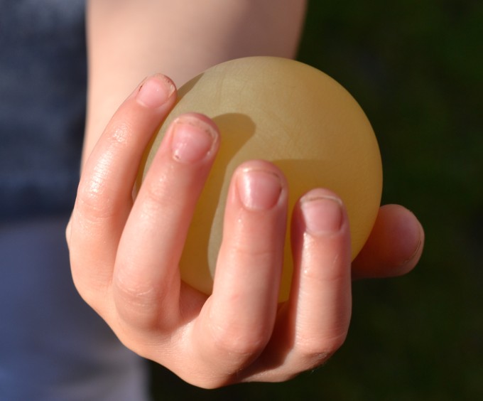 Egg with the shell removed by vinegar in a child's hand