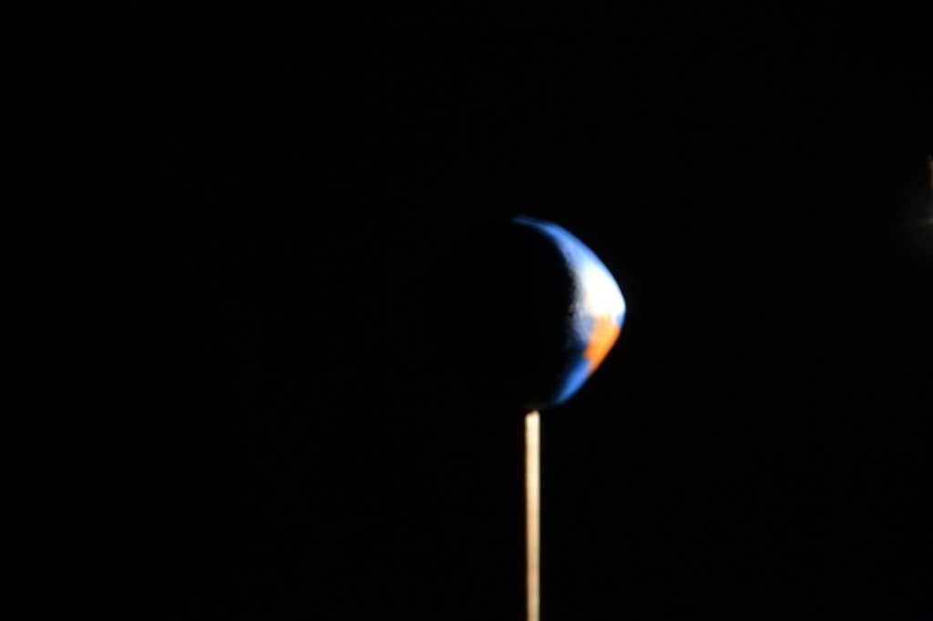 Image of a torch shining on a ball of plasticine made to look like the Earth for a why do we have night and day experiment