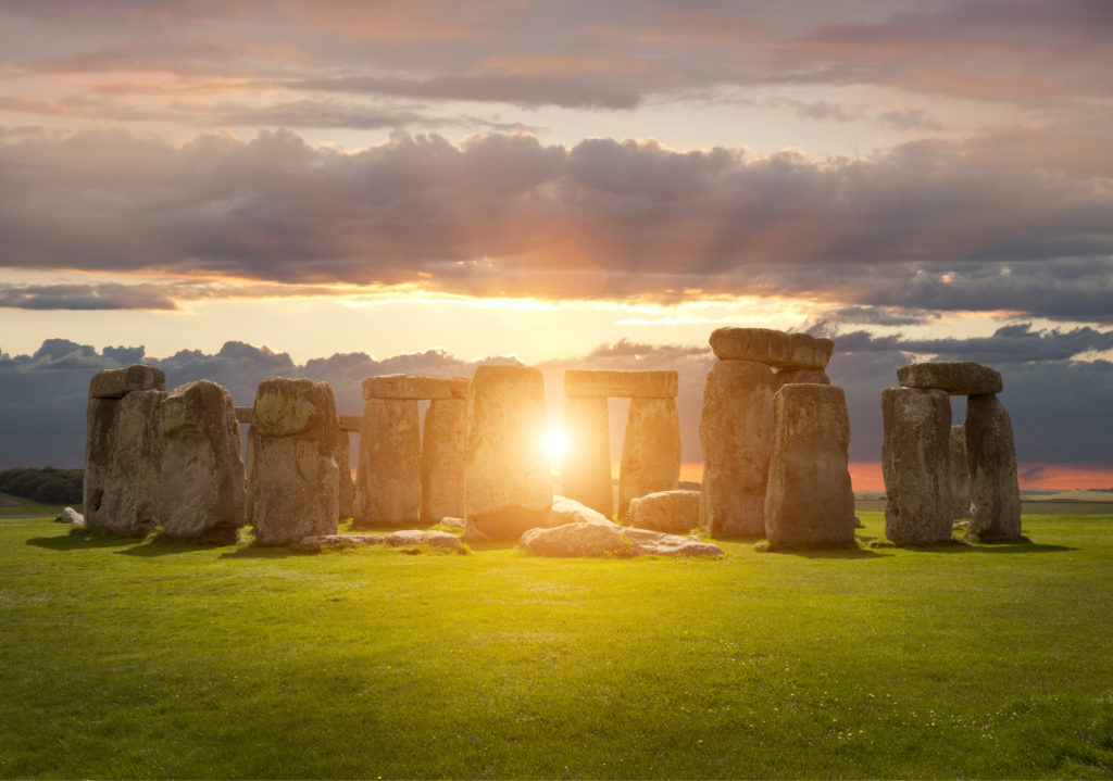 stonehenge with the sun shining through at the summer solstice