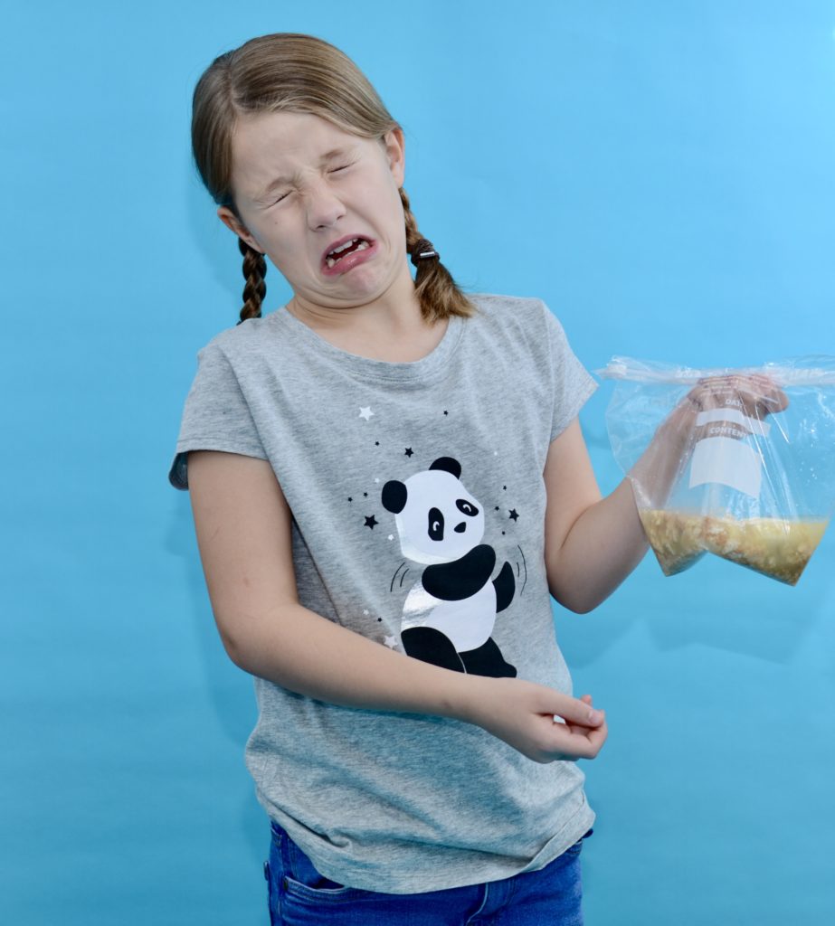 Child holding a bag of mashed banana, orange juice and weetabix