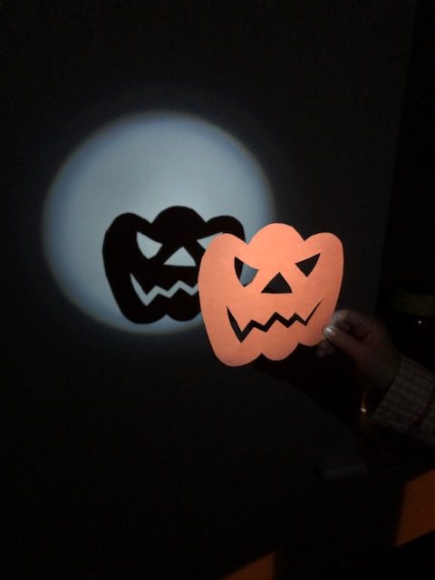 pumpkin shadow puppet with a torch shining behind ut