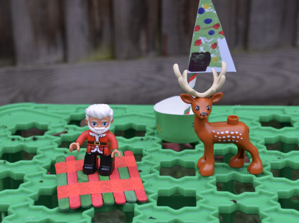 Boats made from lolly sticks and a cardboard container with a DUPLO Santa and reindeer.