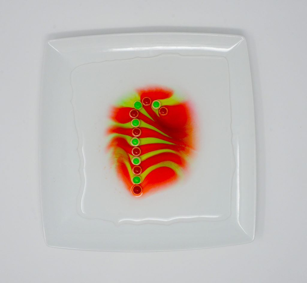 skittles in the shape of a candy cane with colour from the sweets dissolved in the water
