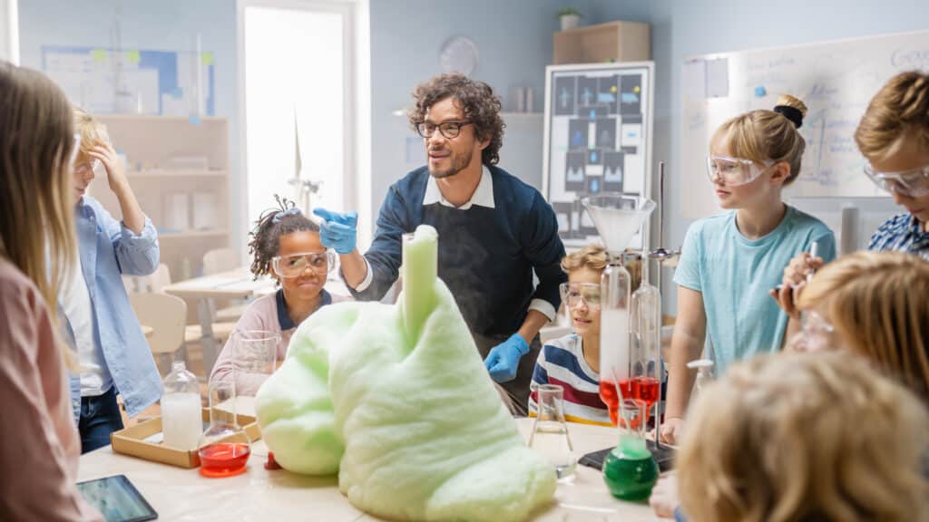 Children and a teacher watching an elephants toothpaste experiment in a classroom.